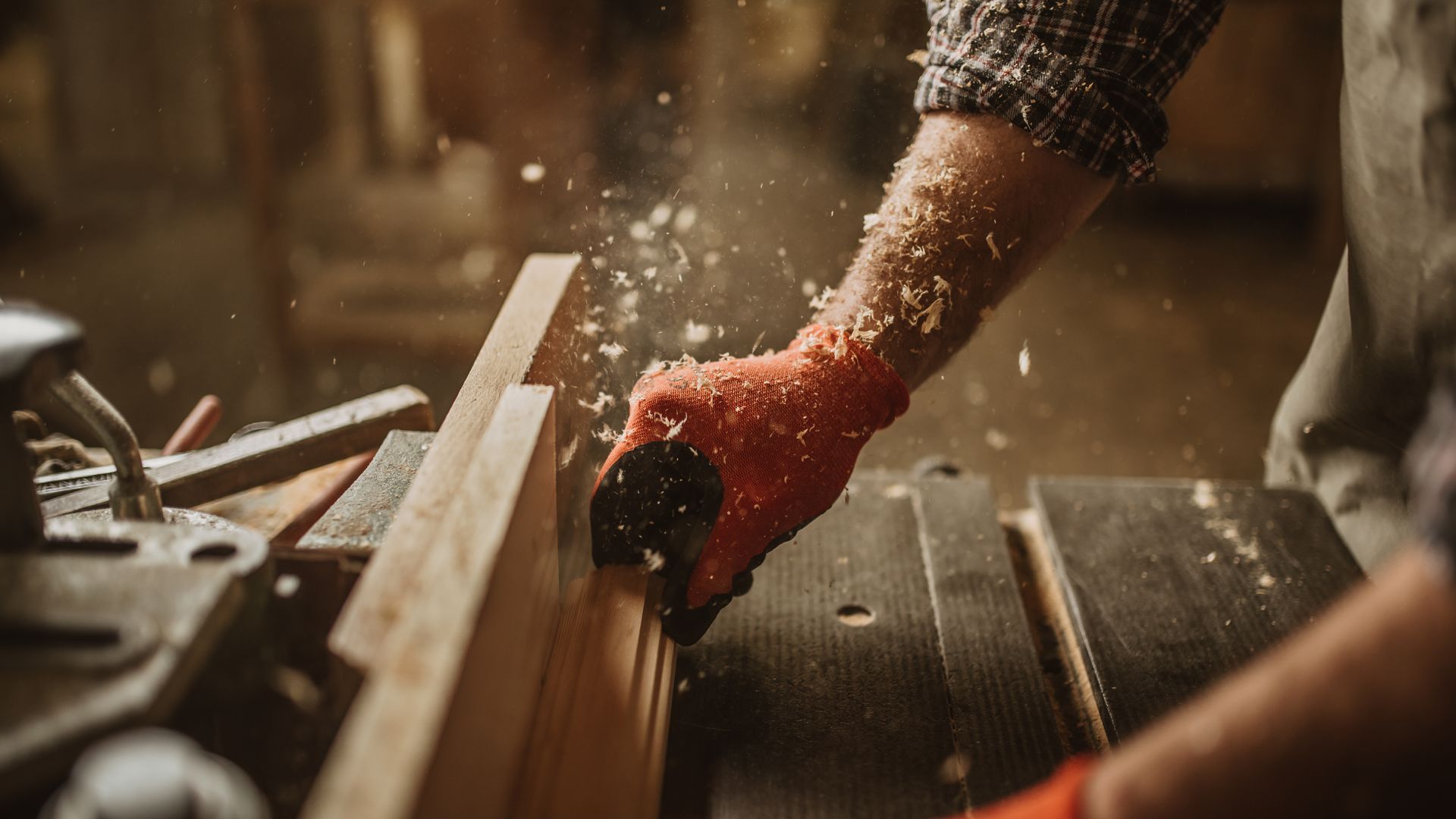 A man is using a plane to cut a piece of wood.