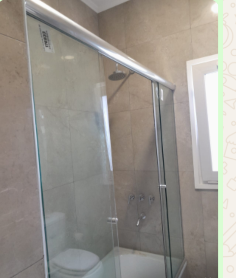 Cabina de ducha con puerta corredera de cristal y sanitario blanco.