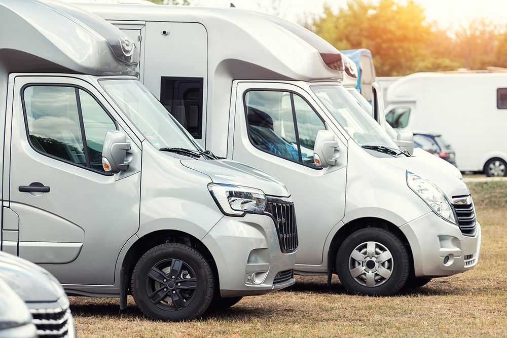 A row of camper vans parked next to each other in a field.