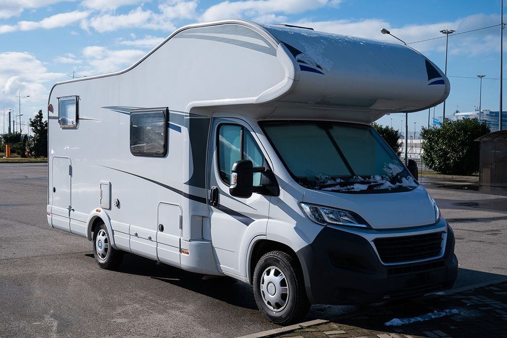A white rv is parked in a parking lot.