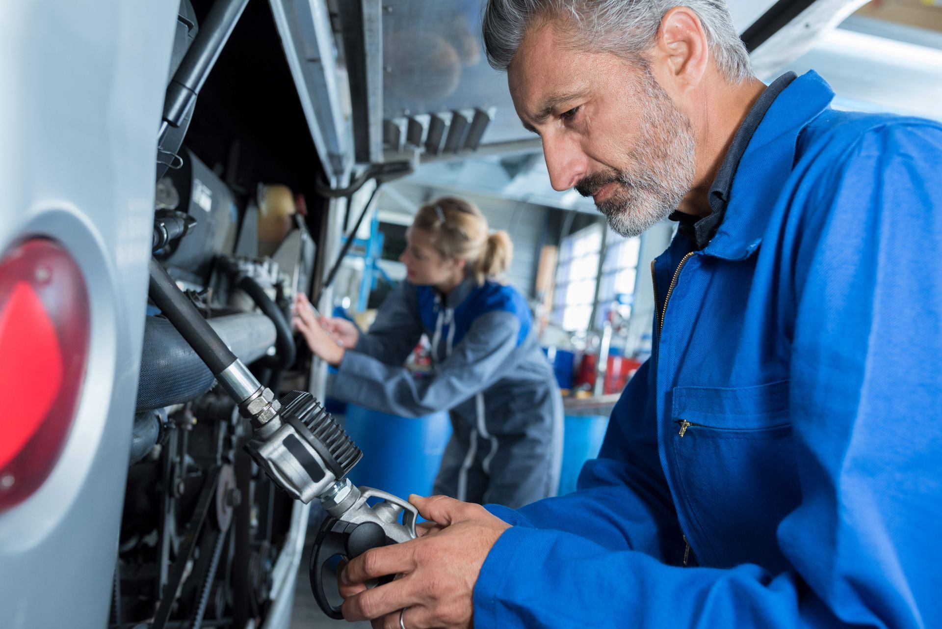 Mechanics in blue uniforms are performing RV repair services on a motorhome.