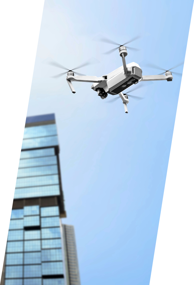 Drone flying near a tall, glass-faced skyscraper against a blue sky.