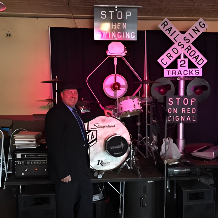 A man stands in front of a drum set and a sign that says stop on red signal