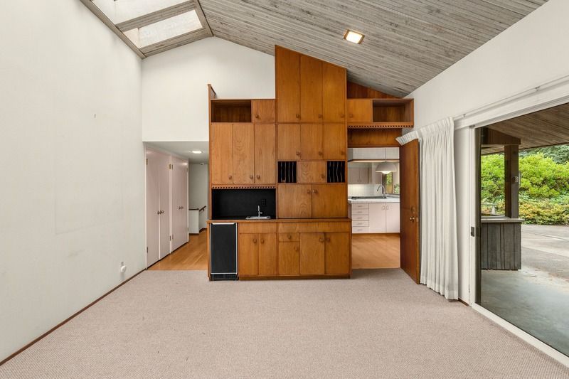 Interior view of a mid-century home with wooden built-ins and a sliding glass door.