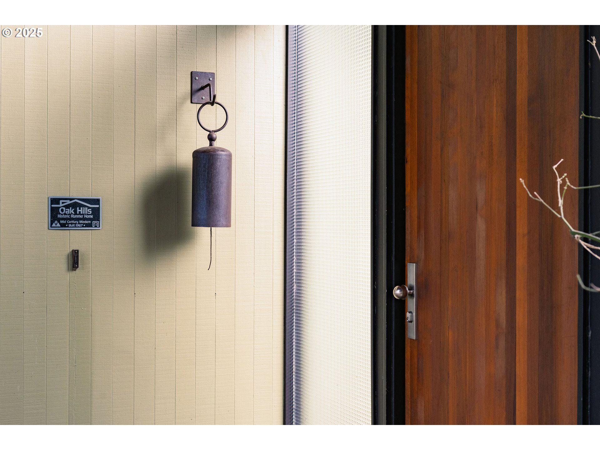 Doorbell and dark wooden door beside a textured cream-colored wall.
