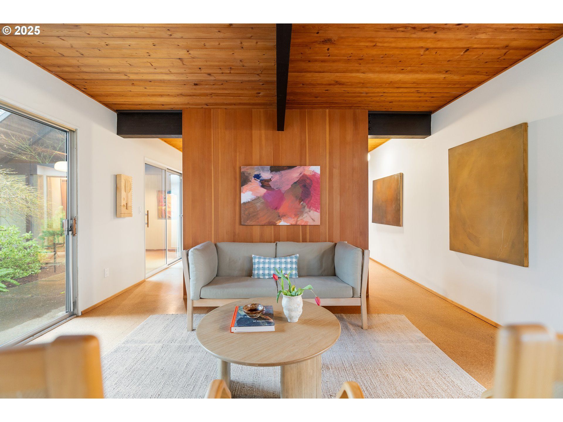Living room with wood paneling, sofa, art, and rug.