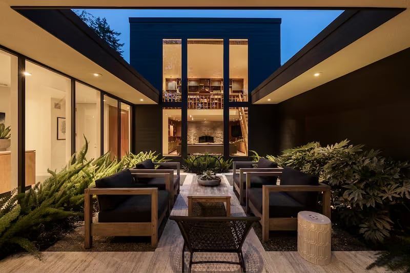 Outdoor seating area with couches and plants in a modern home's courtyard at dusk.