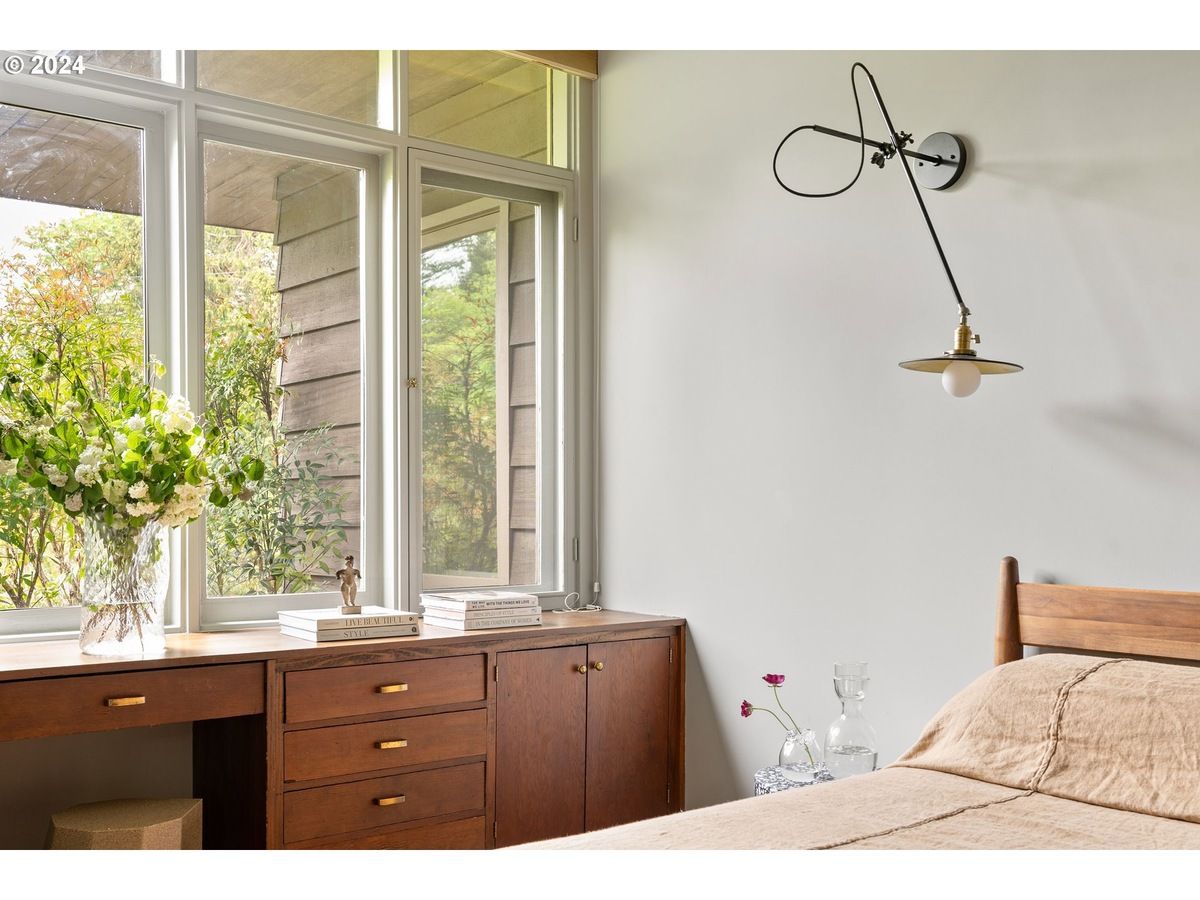 Bedroom interior with a window, wooden desk, and a wall-mounted lamp.