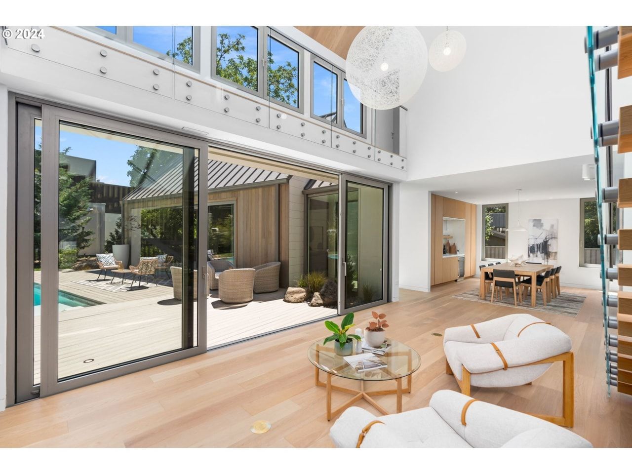 Modern two-story house with light wood siding and a dark metal roof under a blue evening sky.