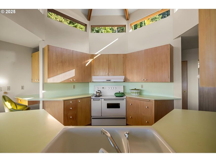 Kitchen with light wood cabinets, white appliances, and pale green countertops.