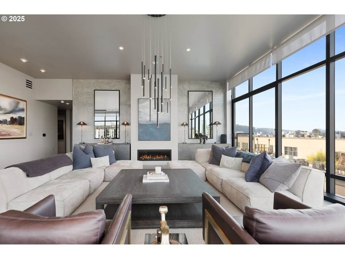 Living room with large windows, modern furniture, fireplace, and city views.