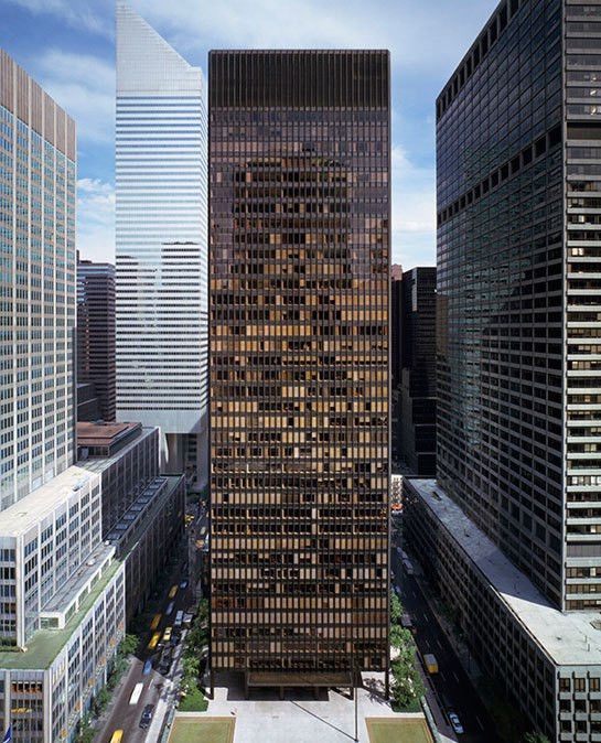 Tall, brown skyscraper flanked by other buildings, seen from a high angle on a city street.