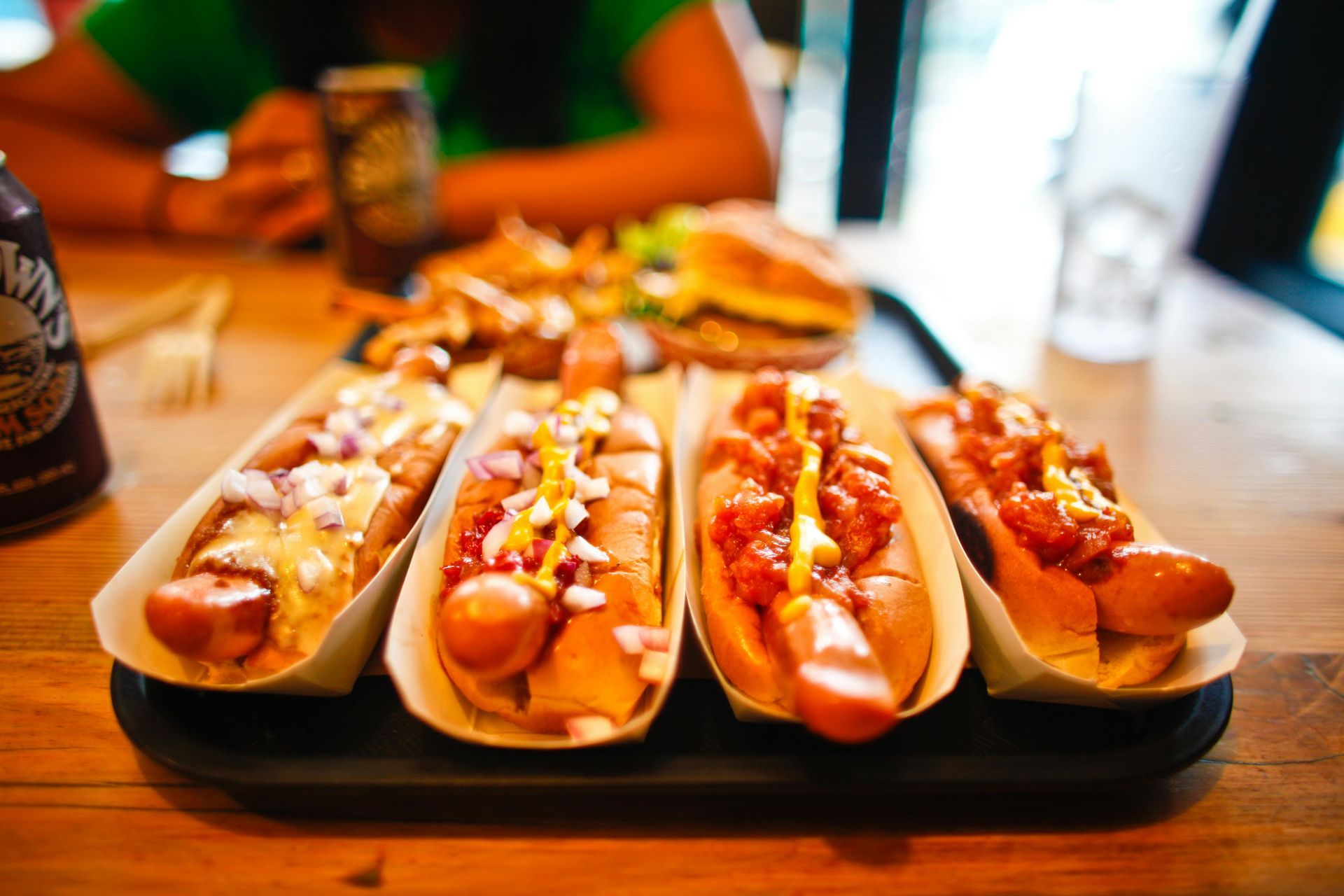 Four hot dogs are sitting on a tray on a table.