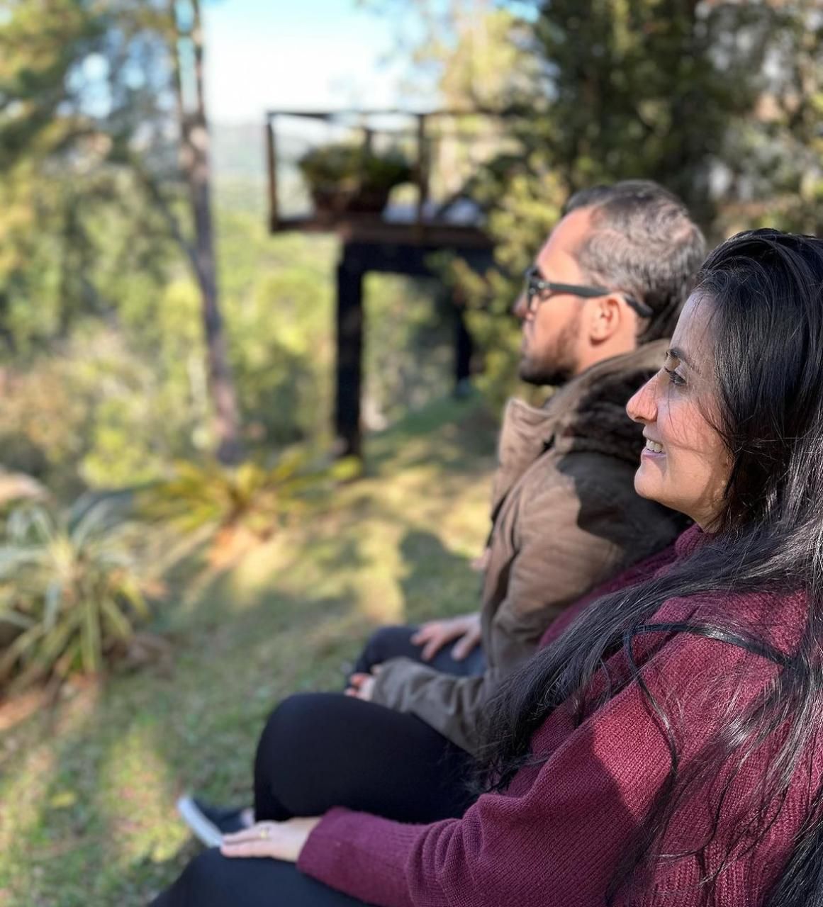 Um homem e uma mulher estão sentados um ao lado do outro na grama.
