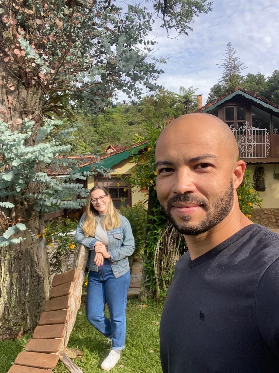 Um homem e uma mulher estão posando para uma foto em frente a uma casa.