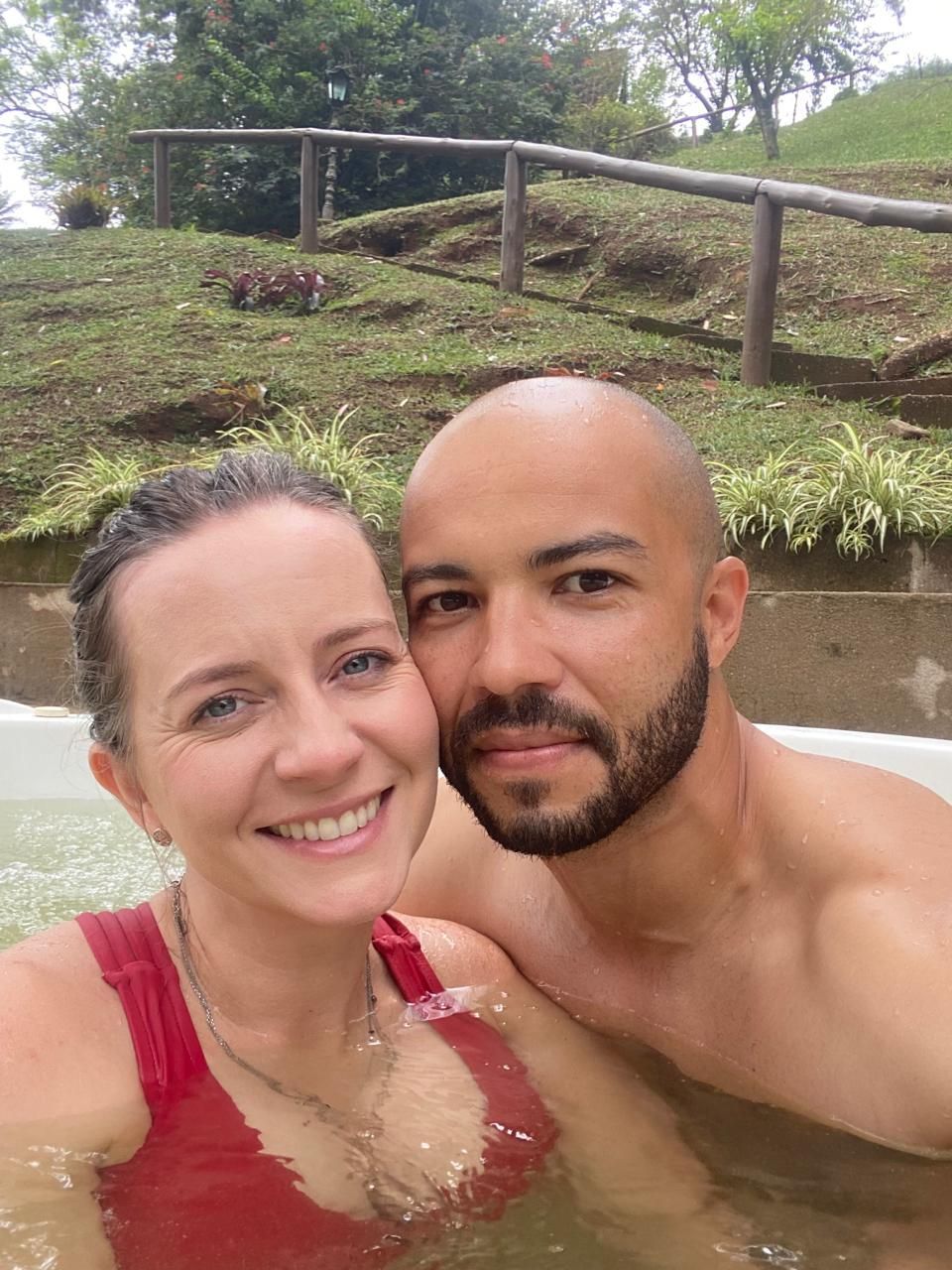 Um homem e uma mulher estão tirando uma selfie em uma banheira de hidromassagem.