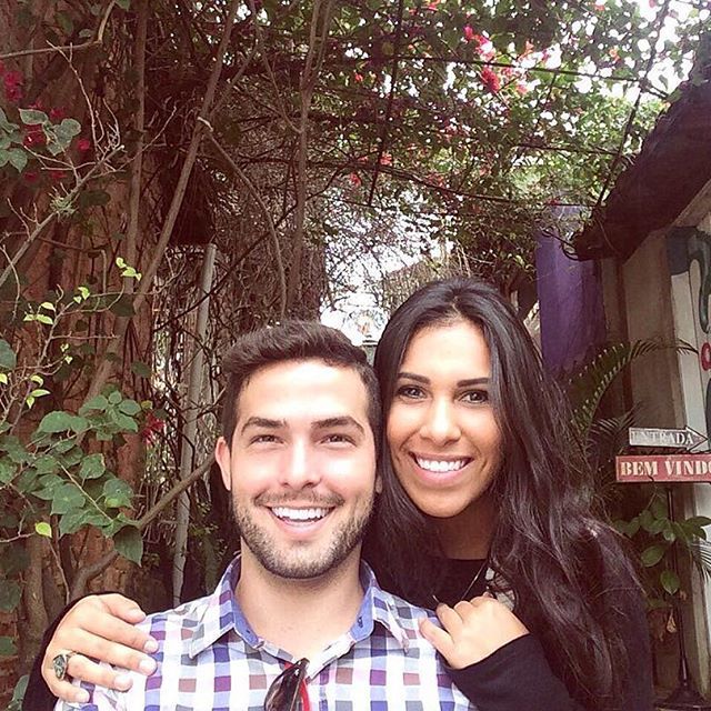 Um homem e uma mulher estão posando para uma foto em frente a uma placa que diz bem vindo