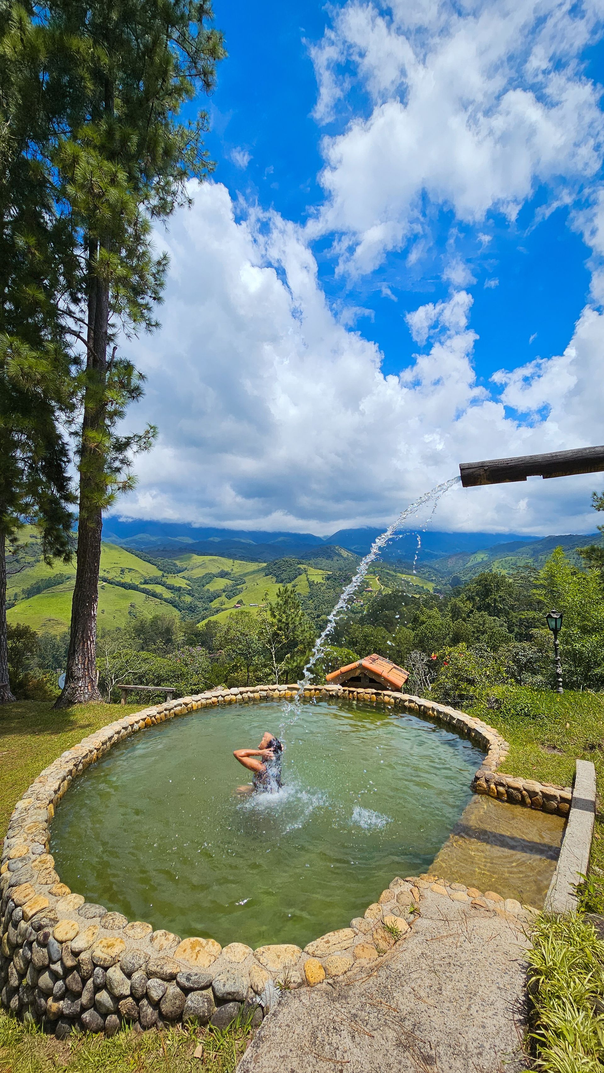 Uma pessoa está nadando em uma piscina com uma fonte jorrando água.