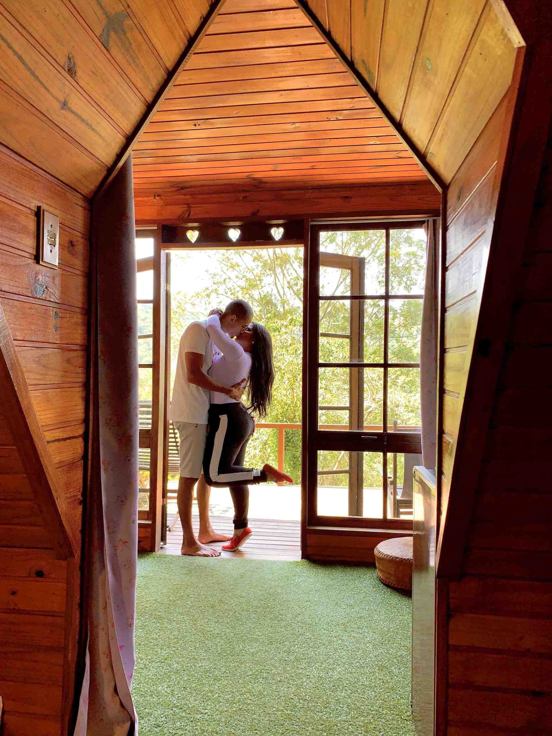 Um homem está segurando uma mulher em seus braços em uma sala de madeira.