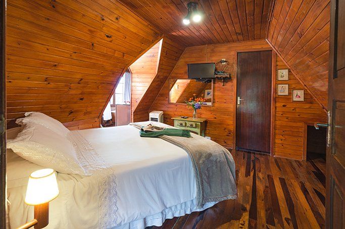 Um quarto em uma cabana de madeira com uma cama e uma televisão.