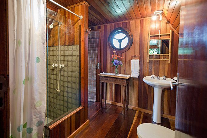 Um banheiro com pia, vaso sanitário, chuveiro e espelho.