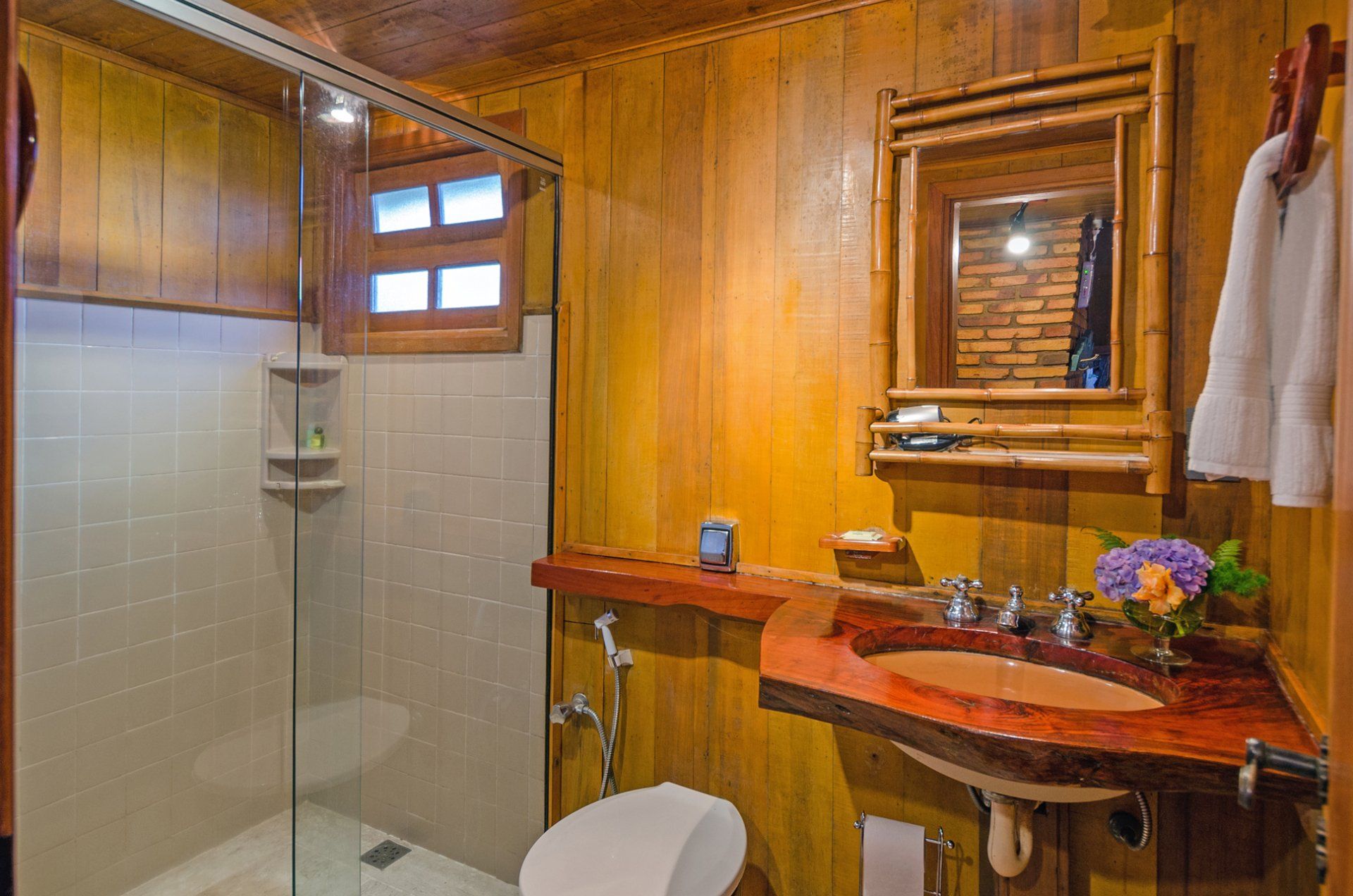 Um banheiro com vaso sanitário, pia, chuveiro e espelho.