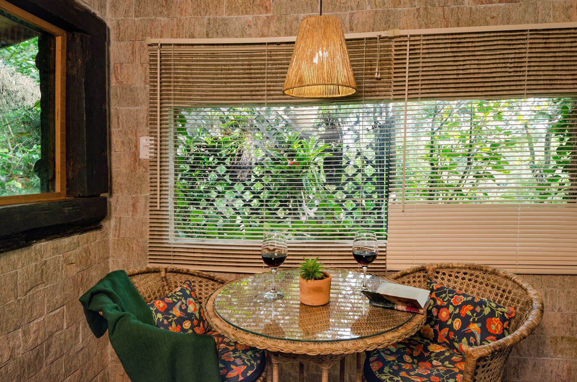 Há uma mesa e cadeiras em frente a uma janela com persianas.