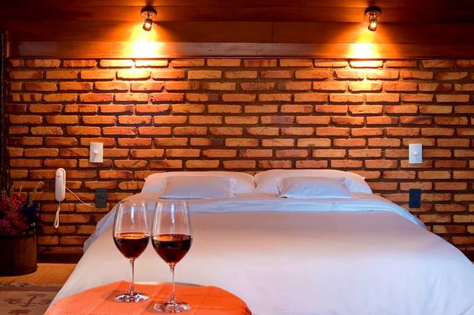 Duas taças de vinho estão sobre uma mesa em frente à cama.