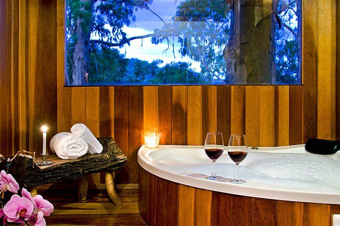 Há uma jacuzzi com duas taças de vinho.