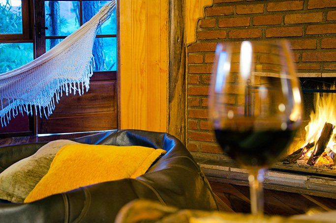 Uma taça de vinho está em frente à lareira na sala de estar.