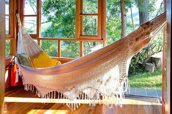 Uma rede está em frente a uma janela com árvores ao fundo