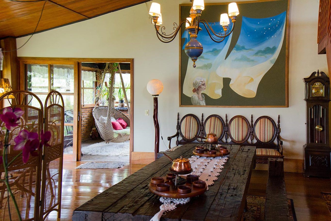 Uma sala de jantar com uma longa mesa de madeira e uma pintura na parede