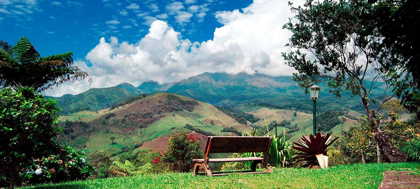 Um banco na grama com montanhas ao fundo