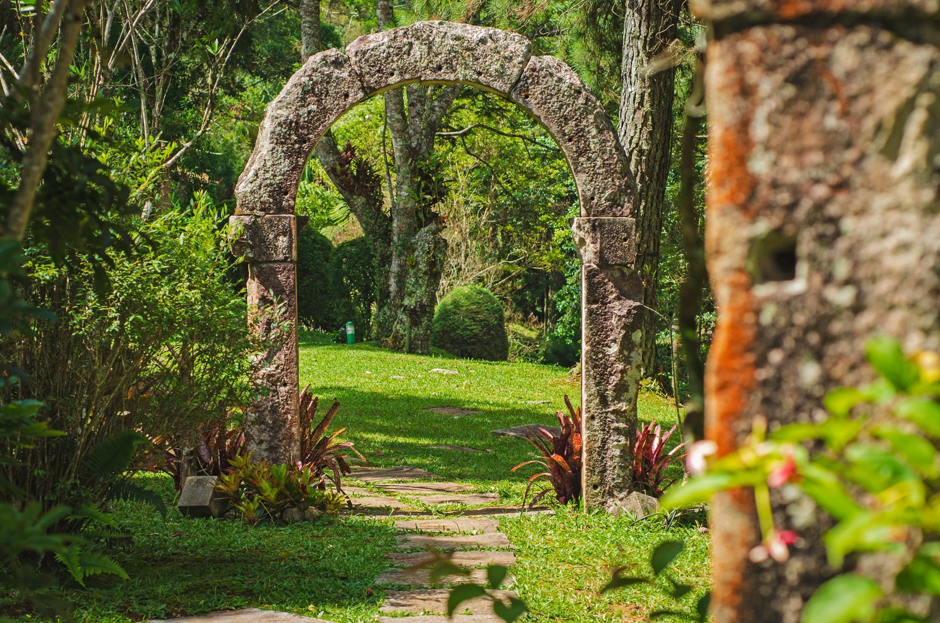 Há um arco de pedra no meio de um jardim.
