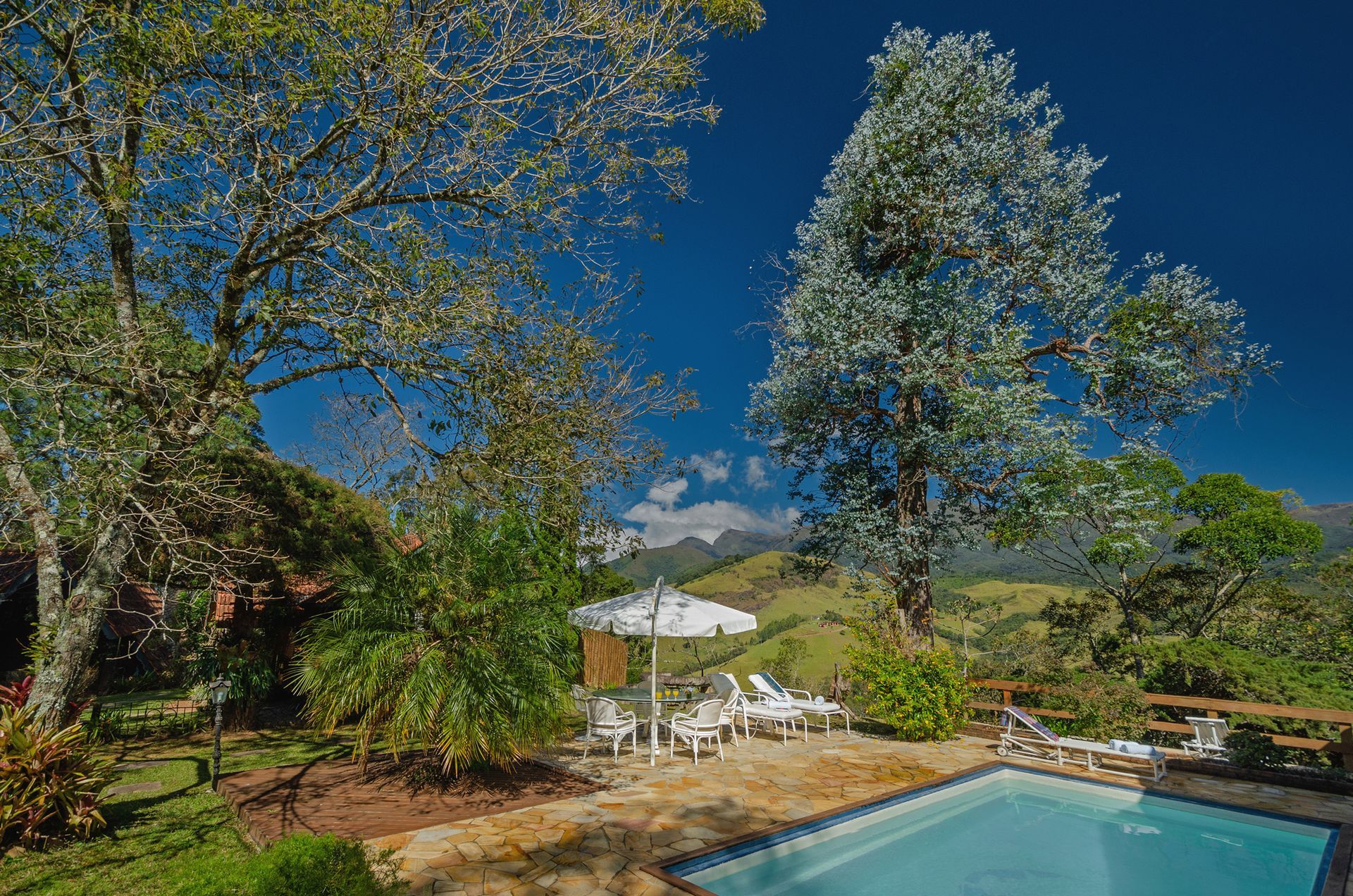 Uma grande piscina cercada por árvores e cadeiras em um dia ensolarado.