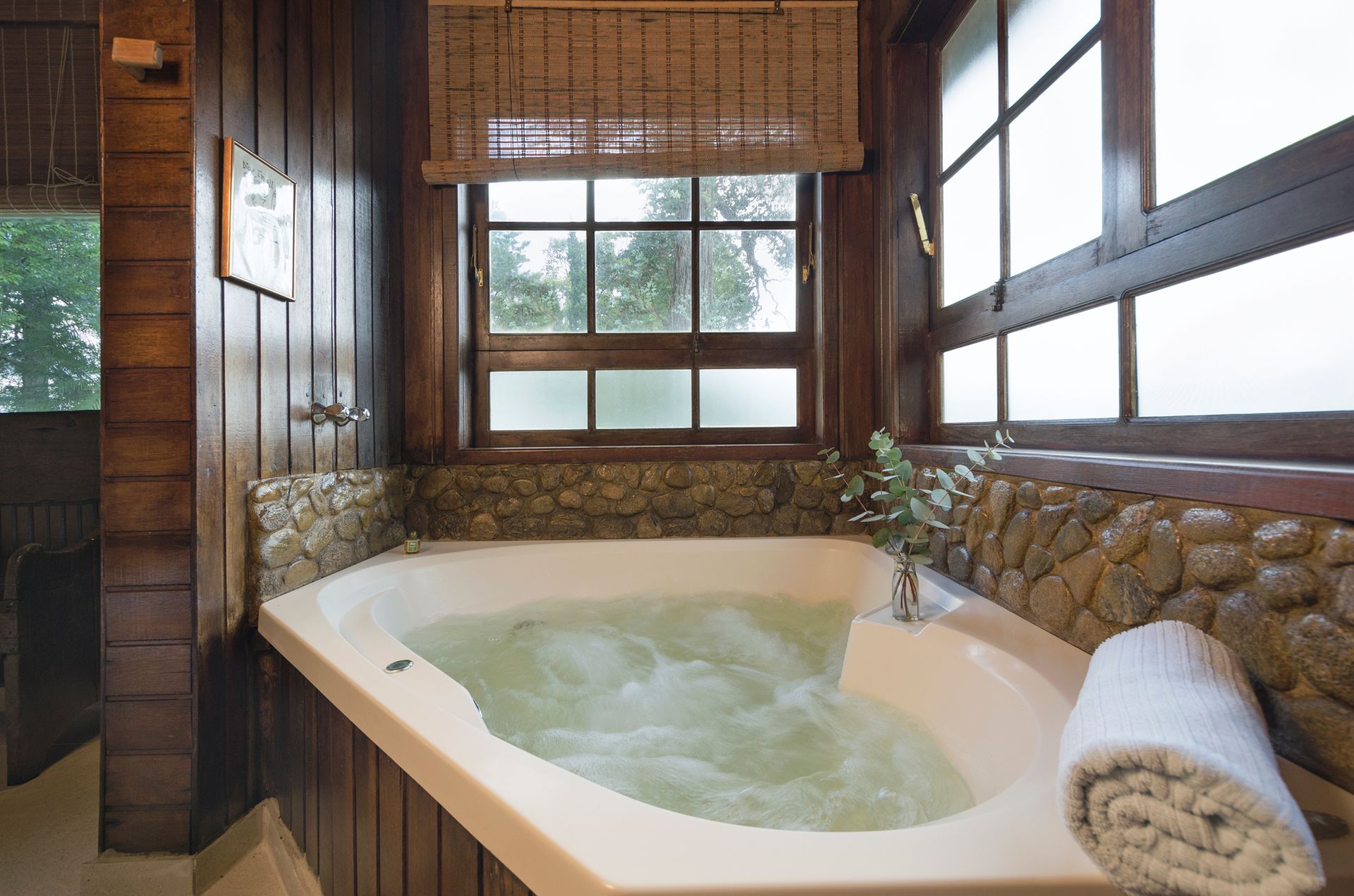 Um banheiro com banheira de hidromassagem e janela