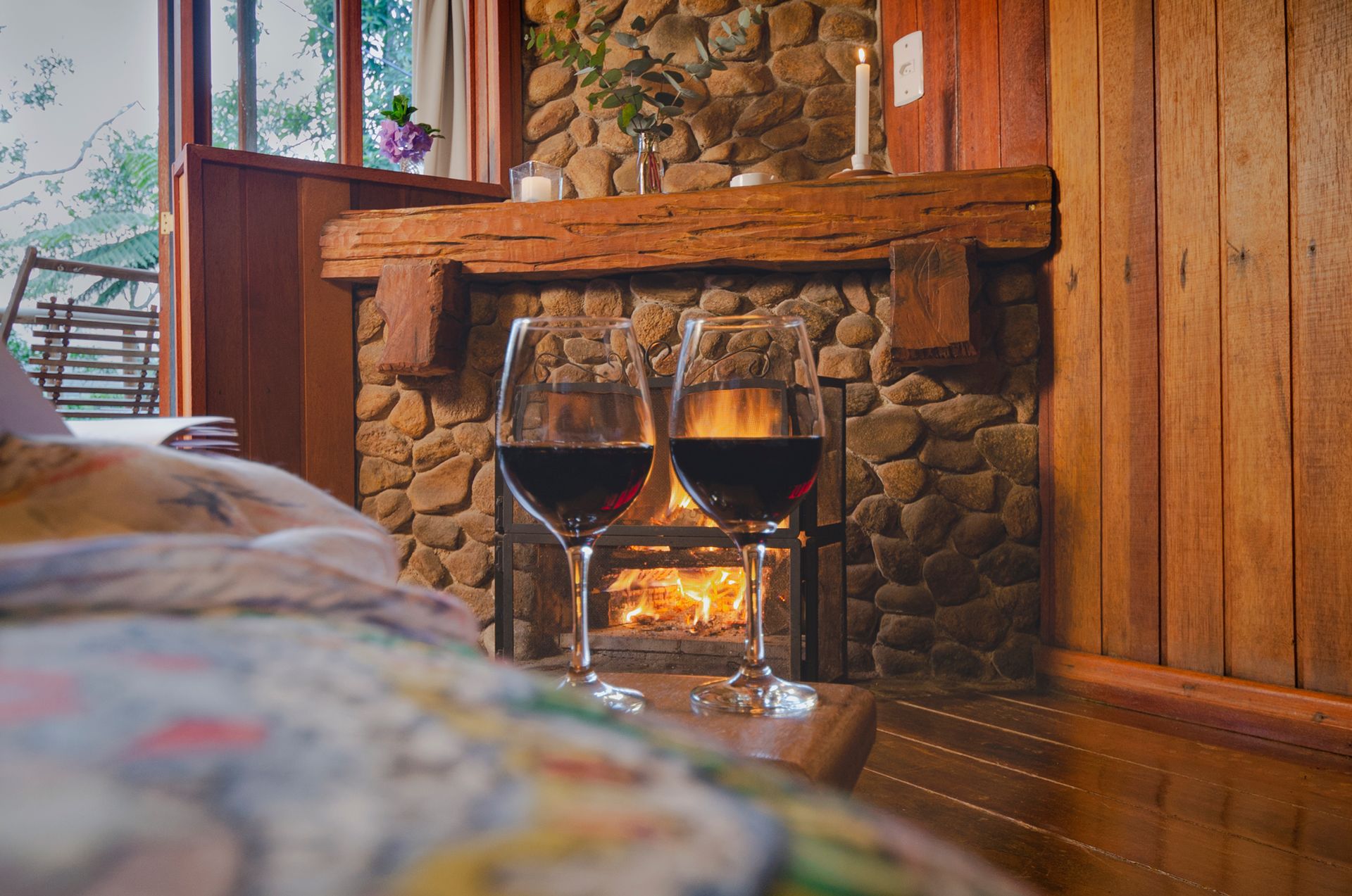 Duas taças de vinho estão em frente a uma lareira de pedra.