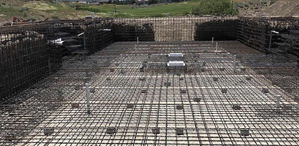 A large swimming pool is being built with a lot of wire mesh.