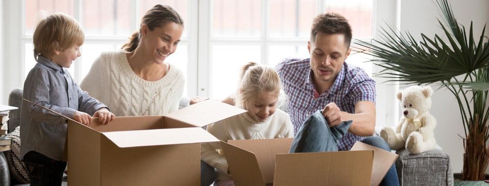 Young happy family with children packing boxes on moving day