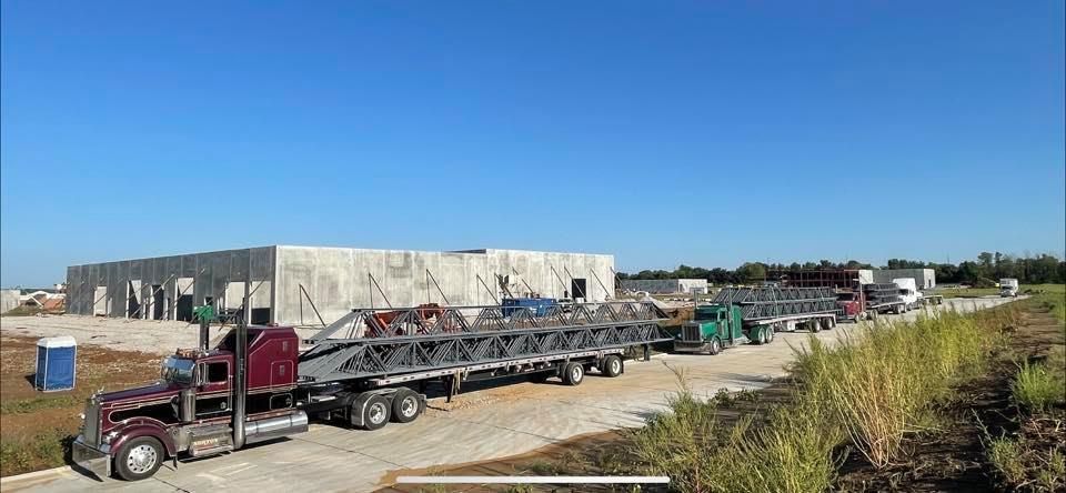 A row of blue semi trucks are parked in a parking lot.