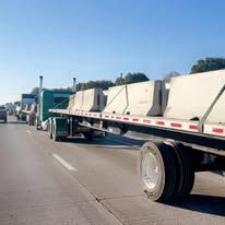 A red semi truck with a white trailer is driving down a highway.