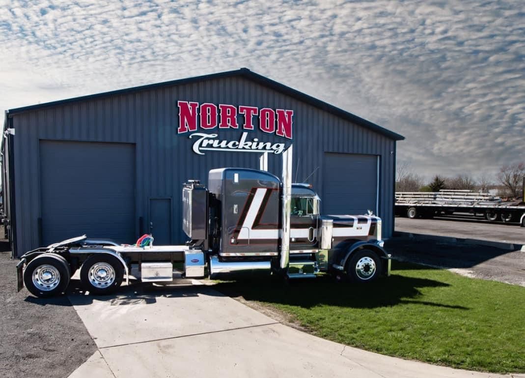 A truck is parked in front of a norton trucking building