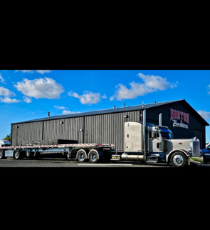 A red semi truck is driving down a dirt road.