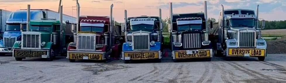 Five semi-trucks parked side-by-side; green, red, blue, black, and silver; 