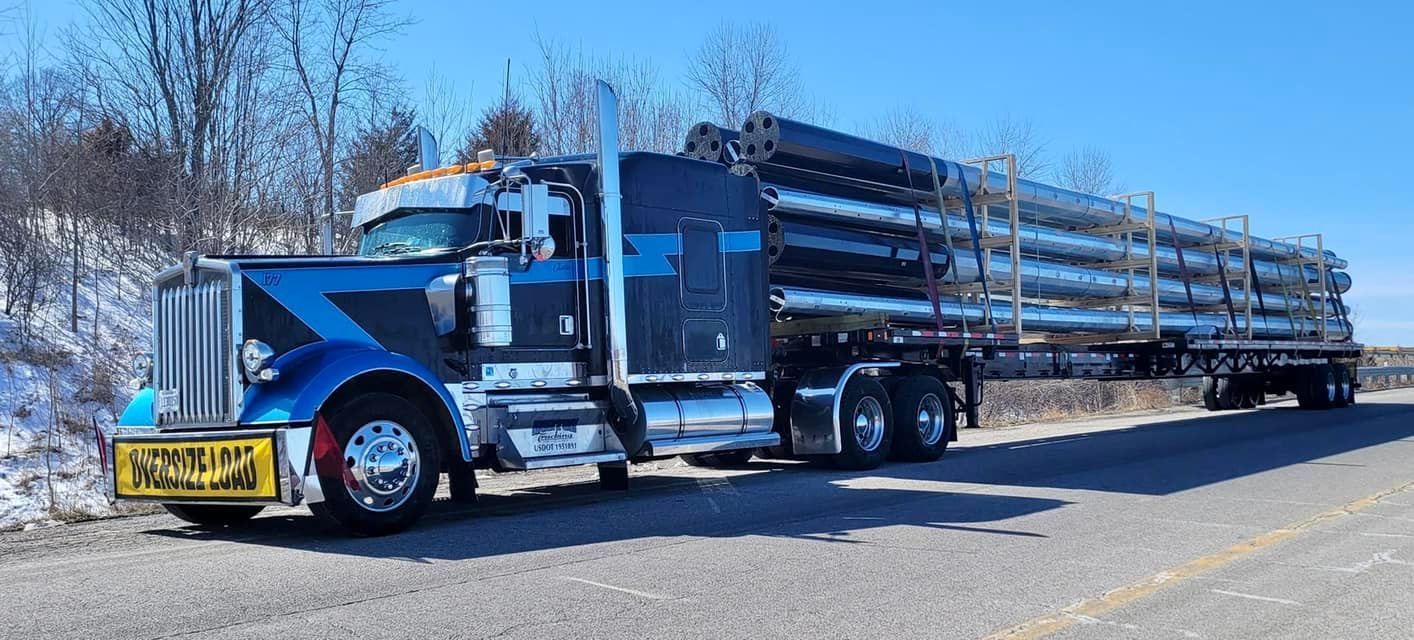 A blue semi truck is parked in front of a brick building.