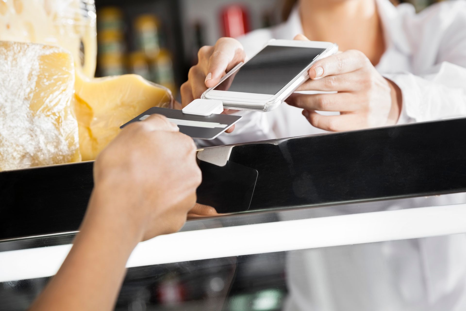 Person paying with a card at a register, using phone to process payment.