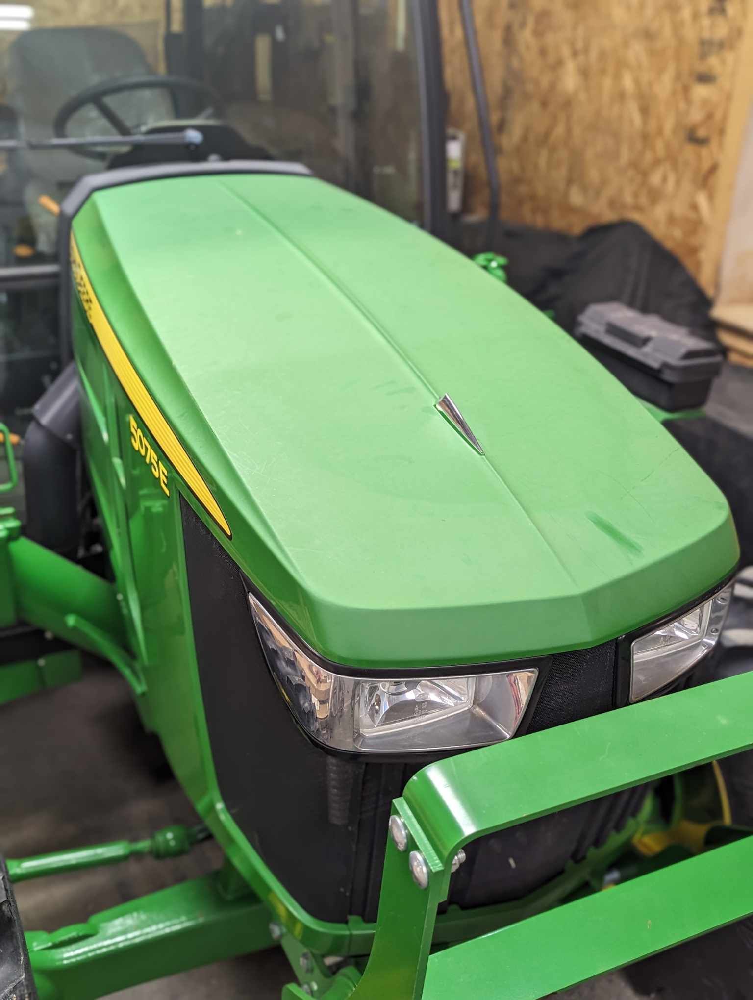 A green john deere tractor is parked in a garage.