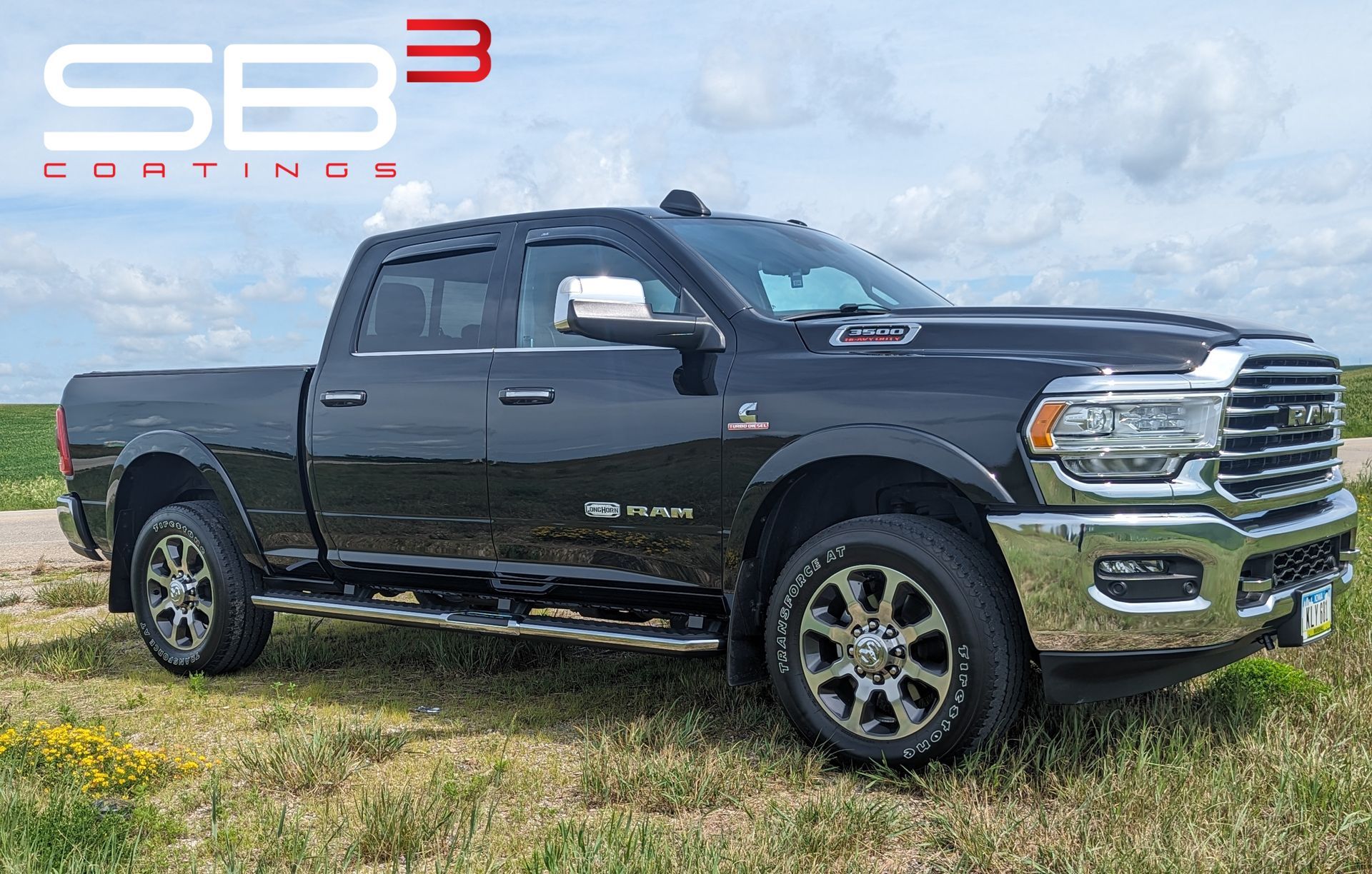 A black dodge ram truck is parked in a grassy field.