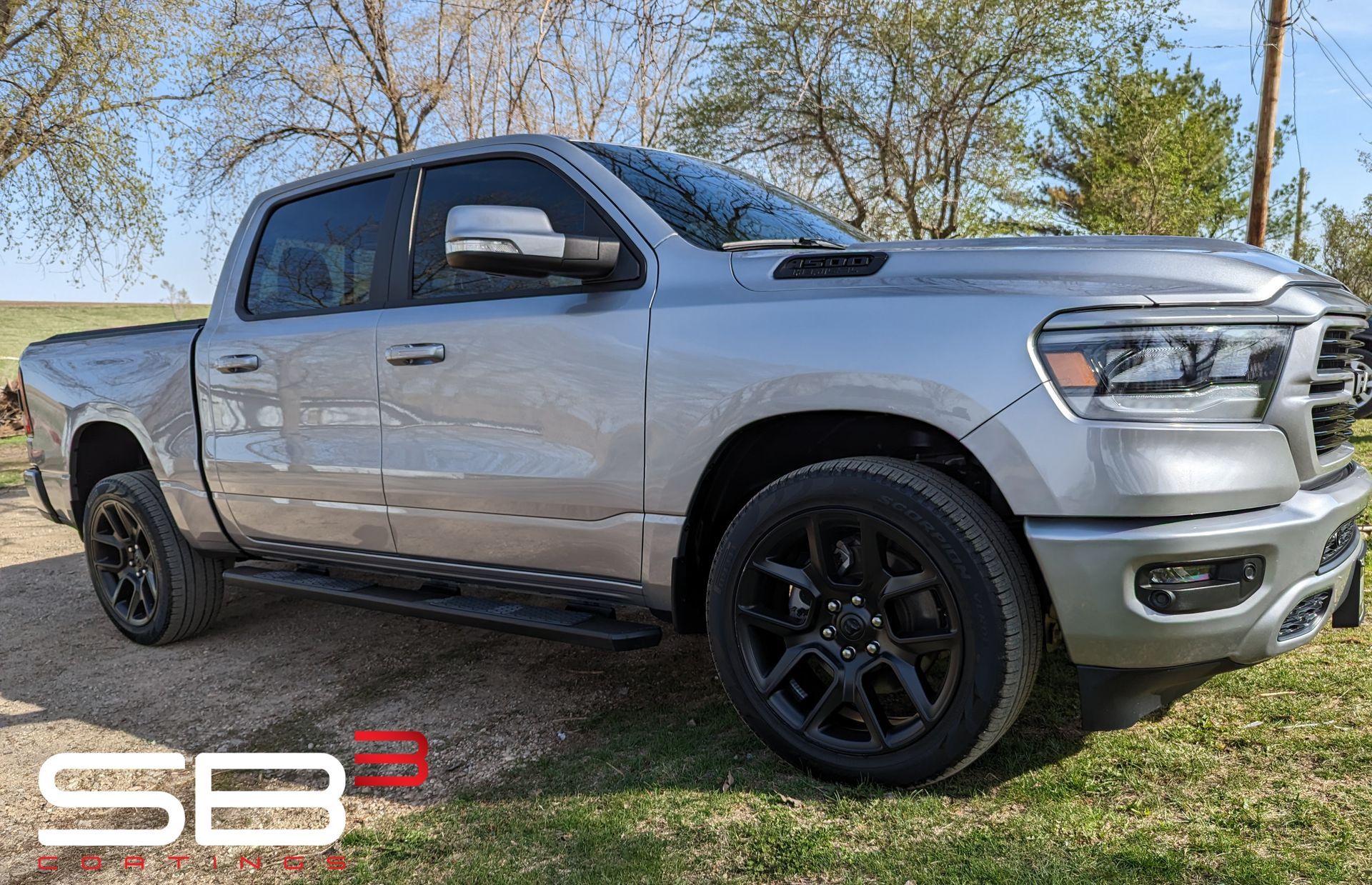 A silver dodge ram truck is parked in a grassy field.