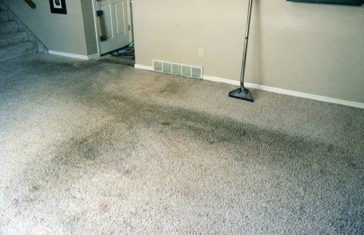 A vacuum cleaner is sitting on a dirty carpet in a living room.